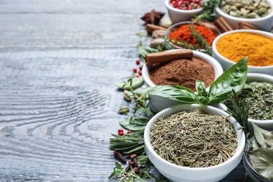 Photo of Different natural spices and herbs on grey wooden table. Space for text