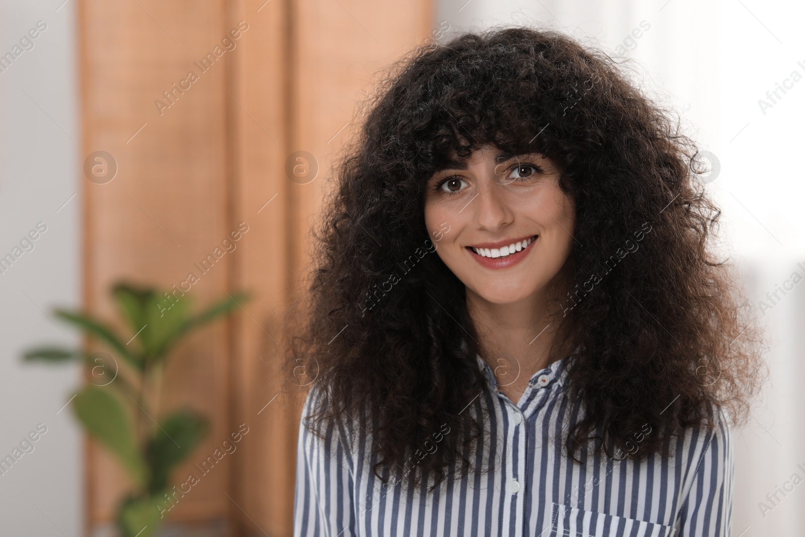 Photo of Portrait of beautiful woman with curly hair indoors. Attractive lady smiling and looking into camera. Space for text