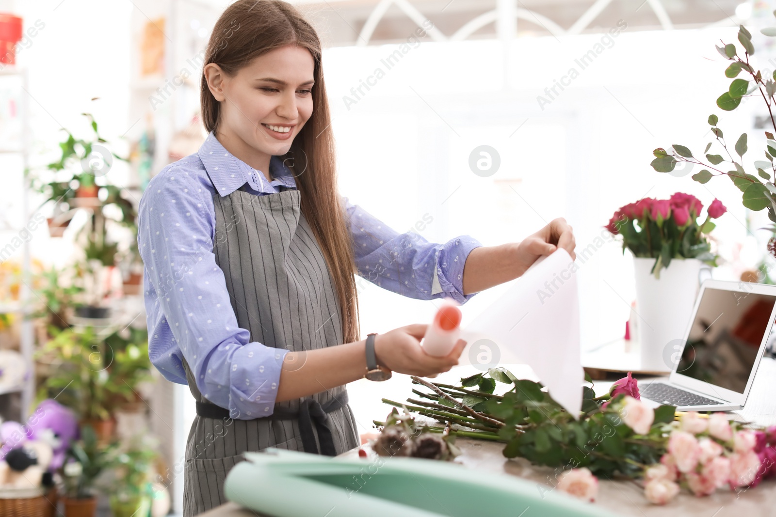 Photo of Female florist making beautiful bouquet in flower shop