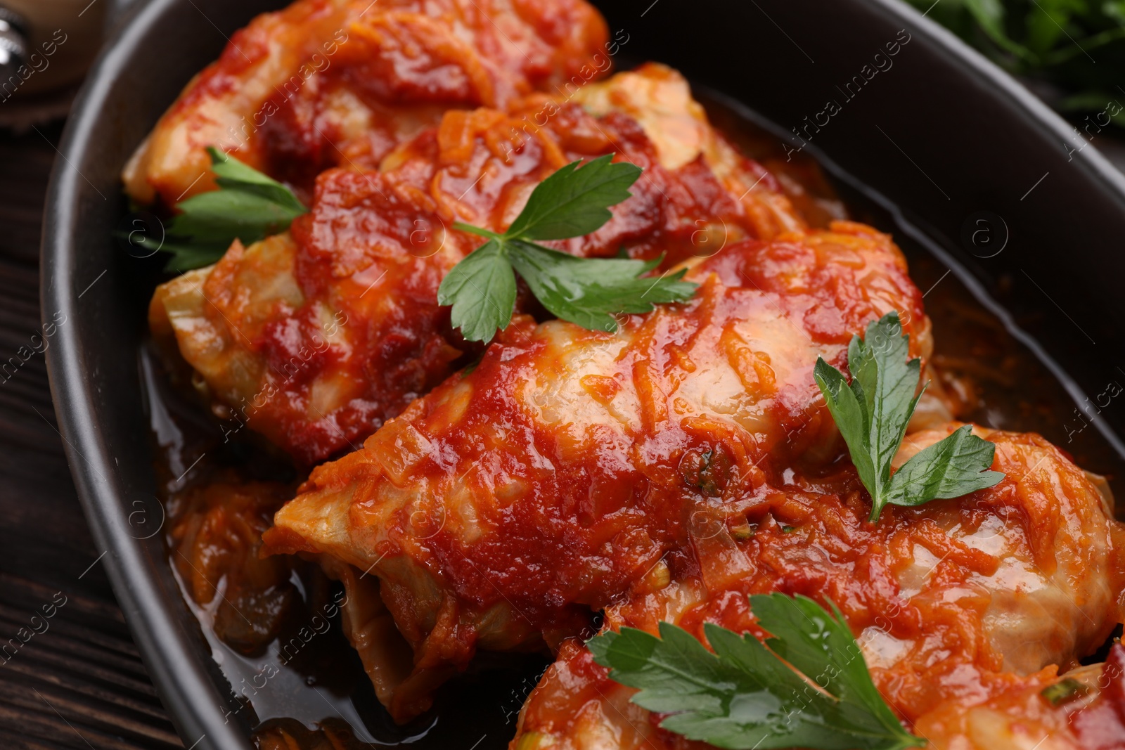 Photo of Delicious stuffed cabbage rolls cooked with homemade tomato sauce on table, closeup