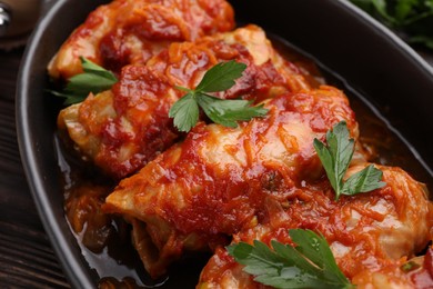 Photo of Delicious stuffed cabbage rolls cooked with homemade tomato sauce on table, closeup