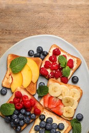 Photo of Tasty toasts with different spreads and fruits on wooden table, top view. Space for text