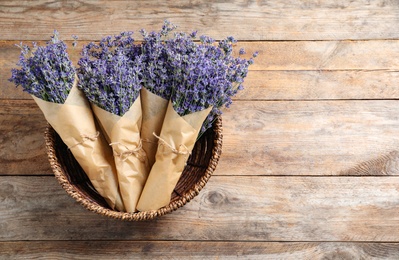 Photo of Fresh lavender flowers in basket on wooden table, top view. Space for text