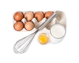 Photo of Metal whisk, raw eggs and glass of milk isolated on white, above view