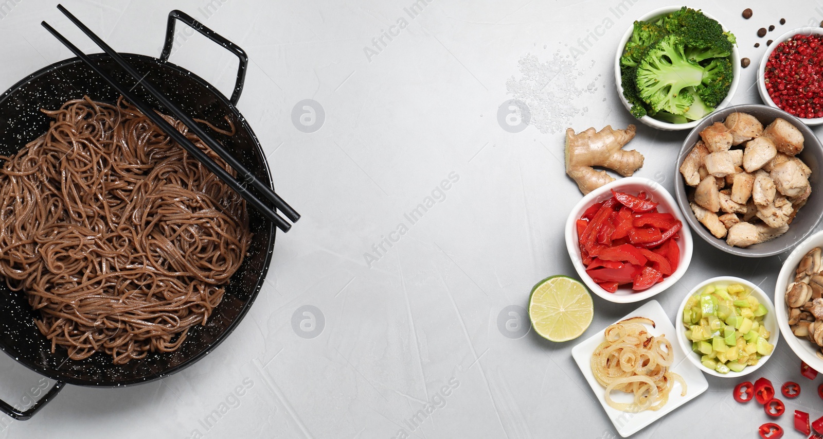 Photo of Wok with noodles, chicken and other products on light grey table, flat lay. Space for text