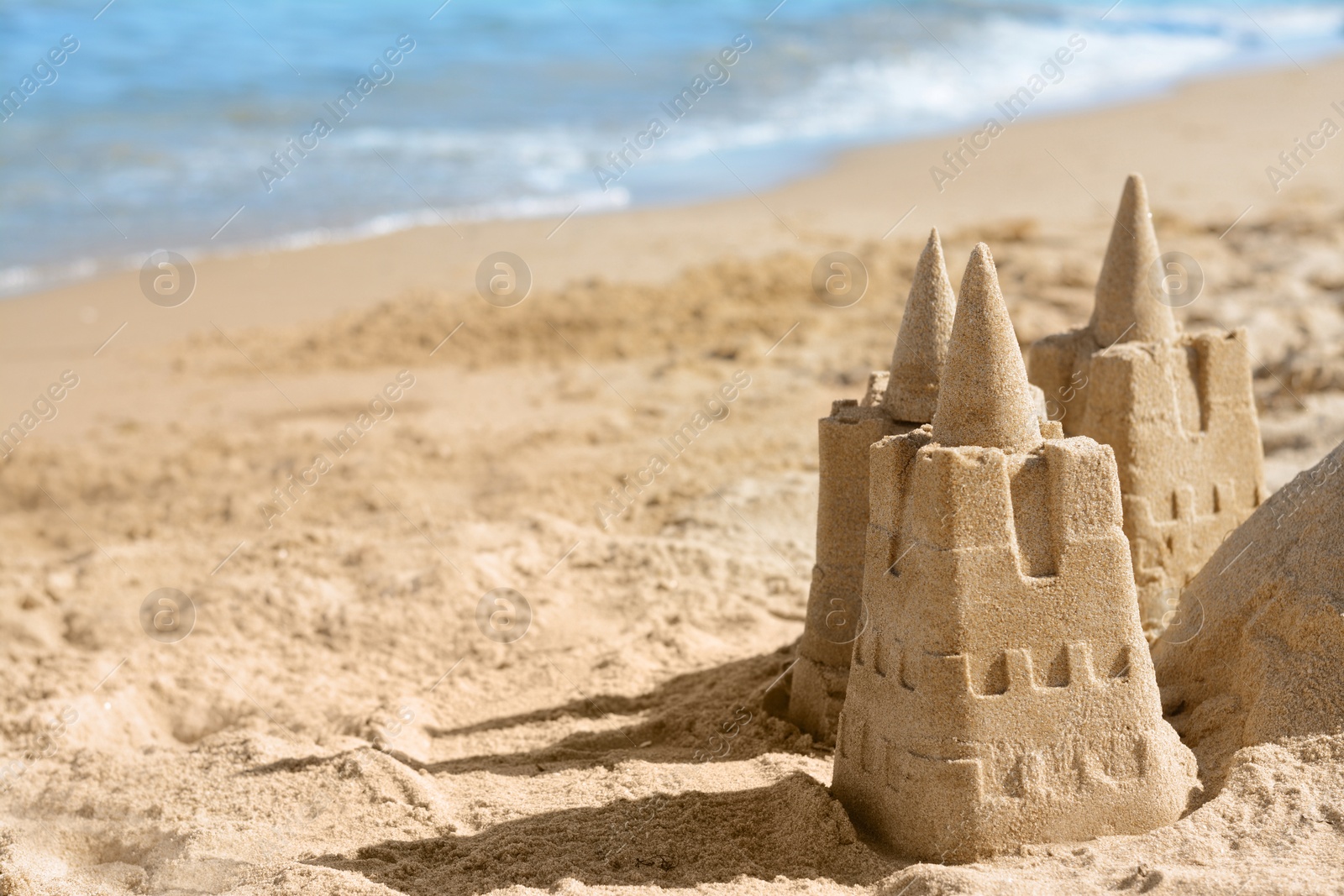 Photo of Beach with sand castle near sea on sunny day. Space for text