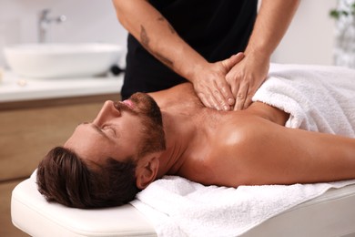 Man receiving professional massage on couch in spa salon