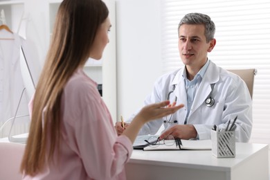 Photo of Gastroenterologist consulting patient at table in clinic