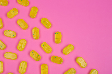 Many delicious lemon drops on pink background, flat lay