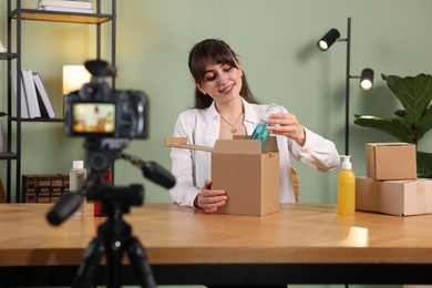 Beauty blogger recording video while showing cosmetic products at home