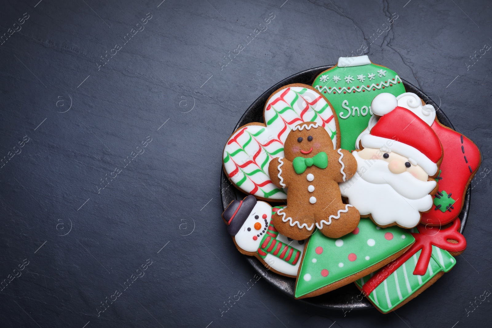 Photo of Delicious gingerbread Christmas cookies on black table, top view. Space for text