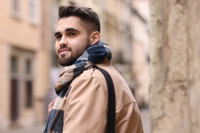 Photo of Smiling man in warm scarf on city street