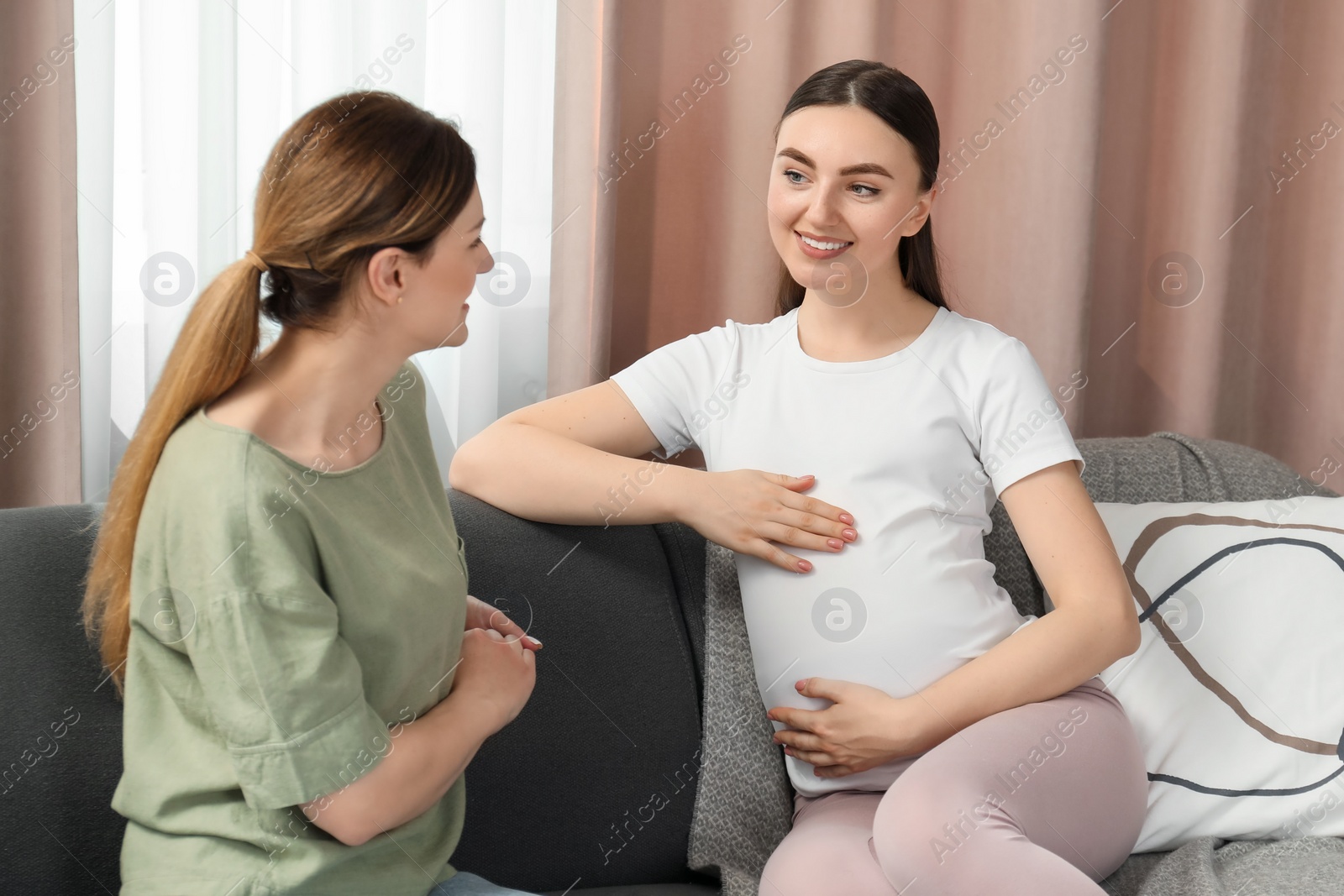 Photo of Doula working with pregnant woman on sofa at home. Preparation for child birth