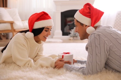 Photo of Couple holding Christmas gift box in living room