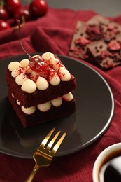 Photo of Piece of red velvet cake and fork on table, closeup