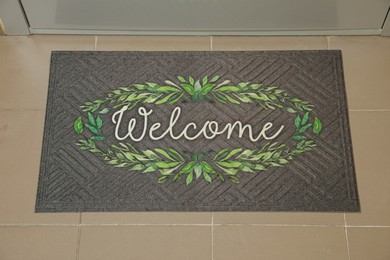 Photo of Beautiful doormat with word Welcome on floor near entrance, above view