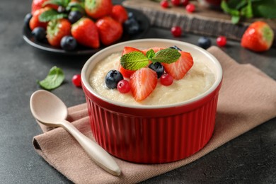 Photo of Delicious semolina pudding with berries and mint served on grey table