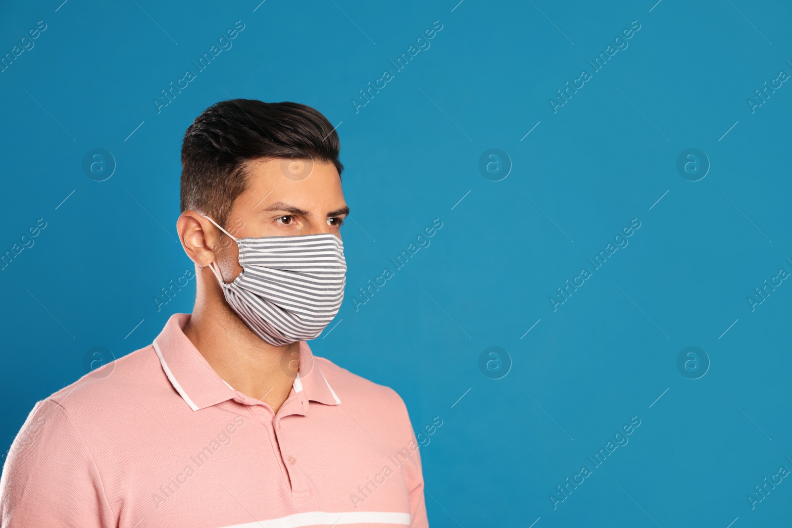 Photo of Man in protective face mask on blue background. Space for text