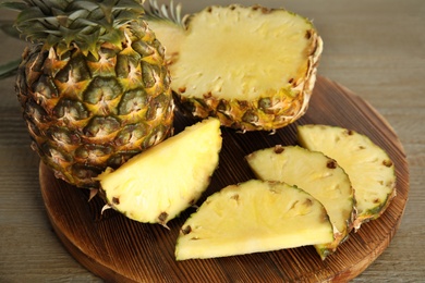 Whole and cut pineapples on wooden table, closeup