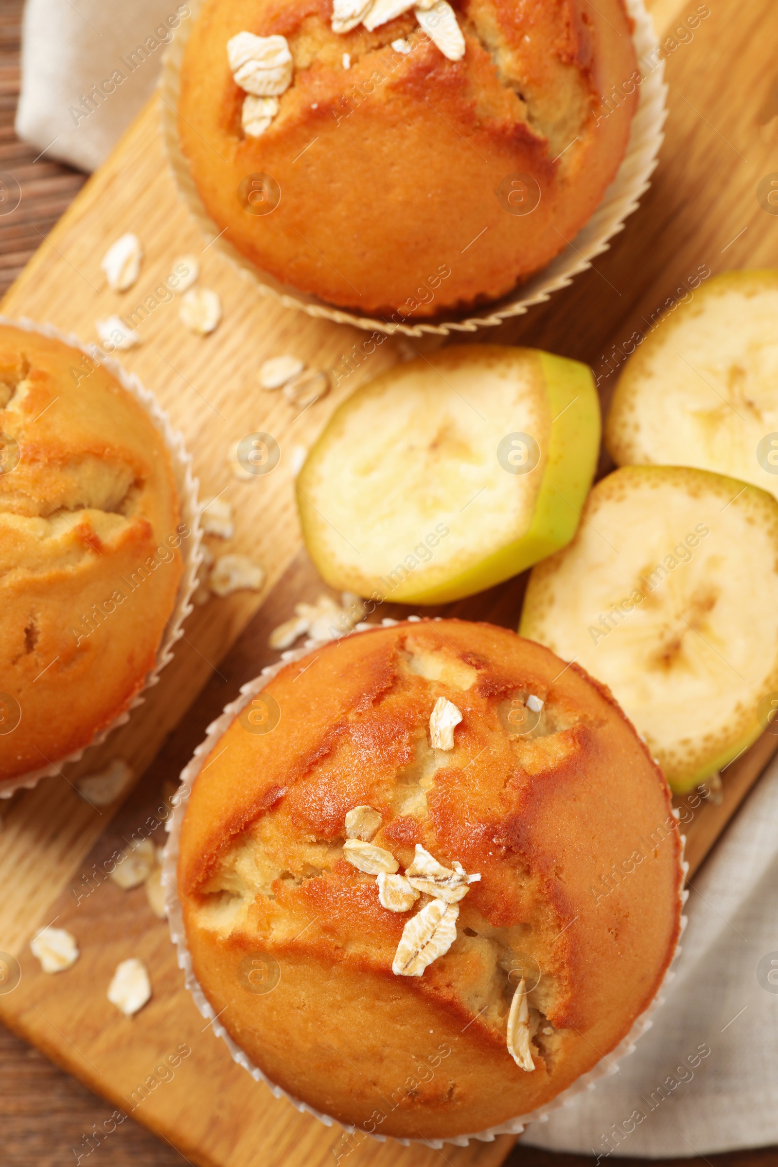 Photo of Tasty muffins served with banana on wooden board, top view