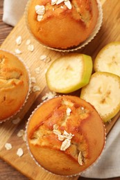 Photo of Tasty muffins served with banana on wooden board, top view