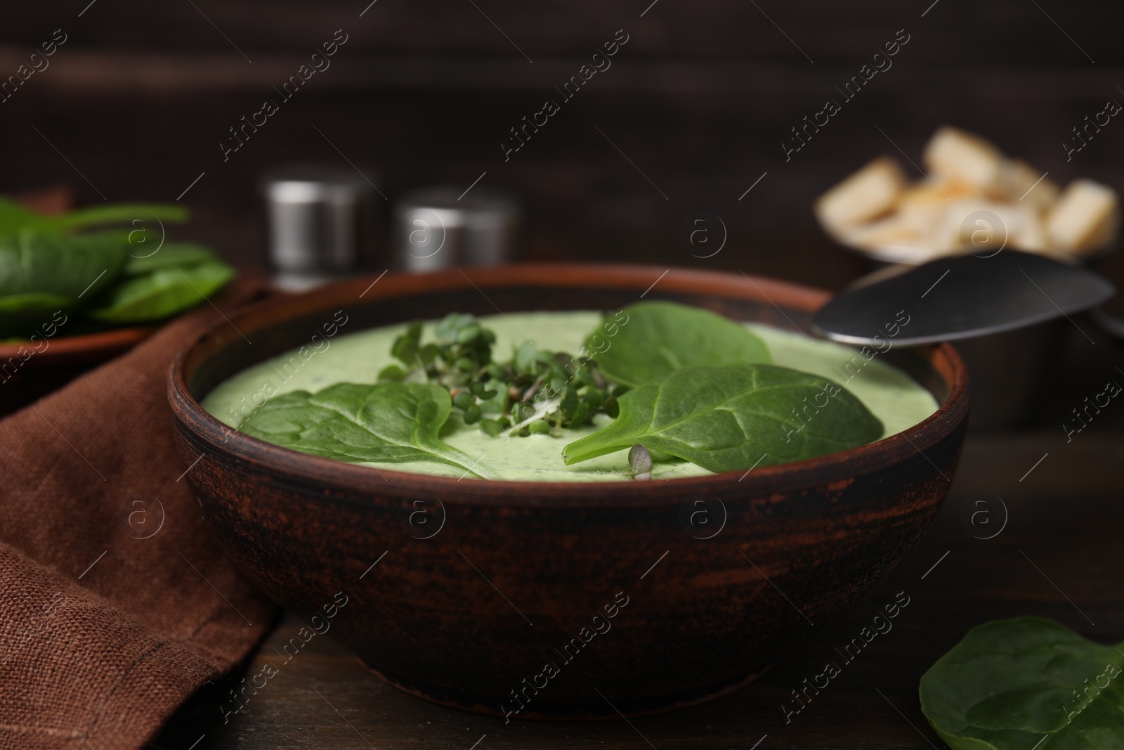 Photo of Delicious spinach cream soup served on wooden table, closeup