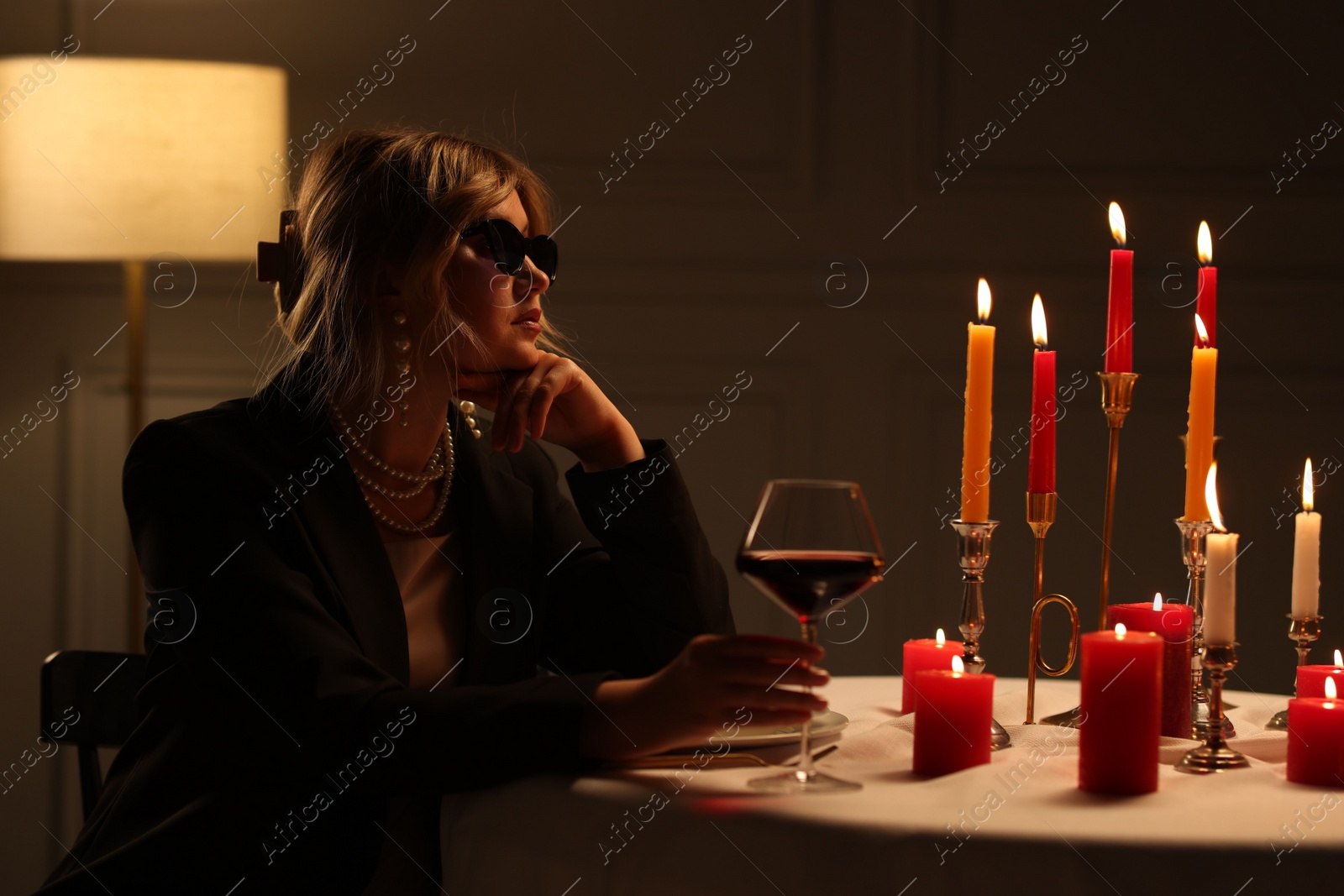 Photo of Beautiful young woman with sunglasses and glass of wine at table in restaurant