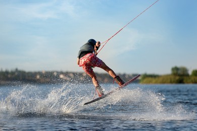 Photo of Teenage wakeboarder doing trick on river. Extreme water sport