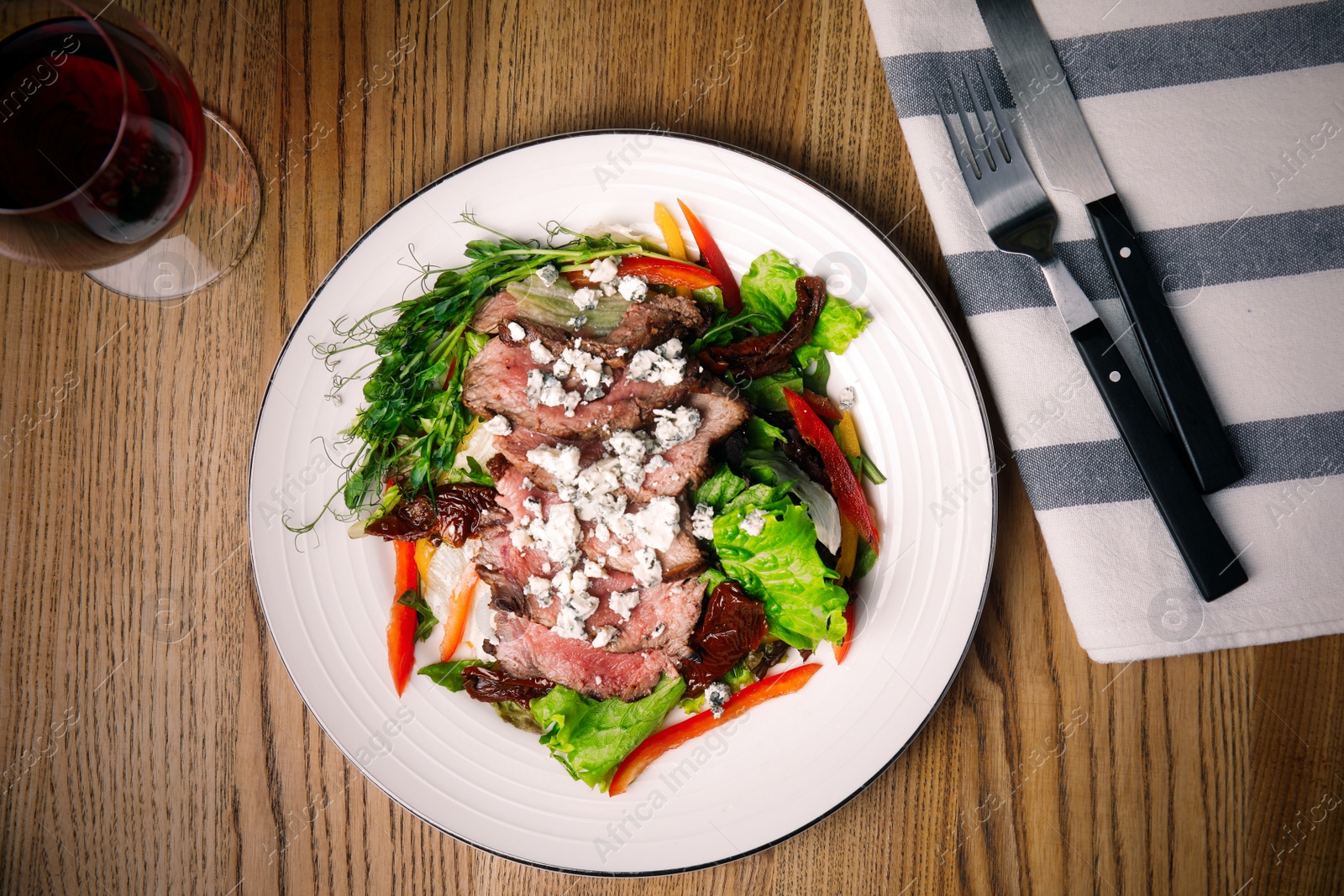 Image of Delicious salad with roasted meat and vegetables served on wooden table, flat lay. Food photography  