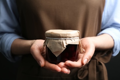 Photo of Woman holding glass jar of pickled cherries, closeup