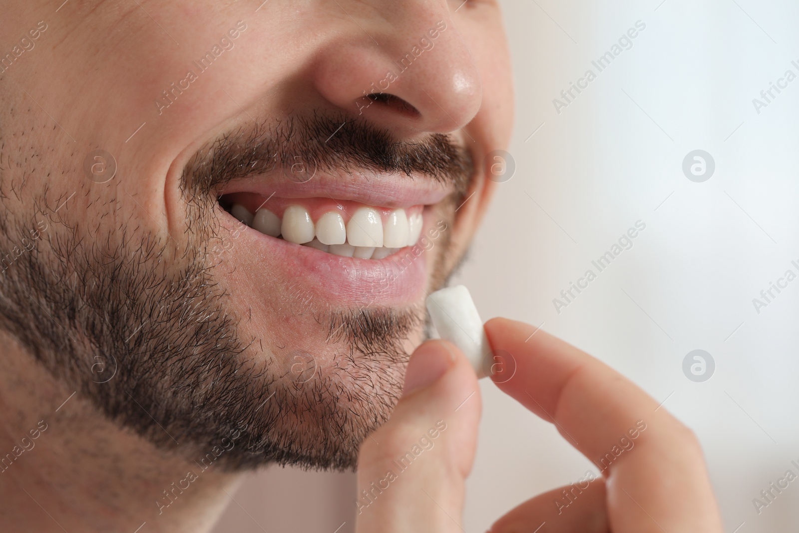 Photo of Man with chewing gum on blurred background, closeup. Space for text