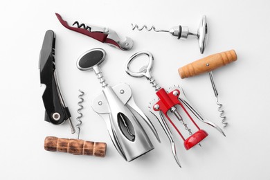 Different corkscrews on white background, flat lay