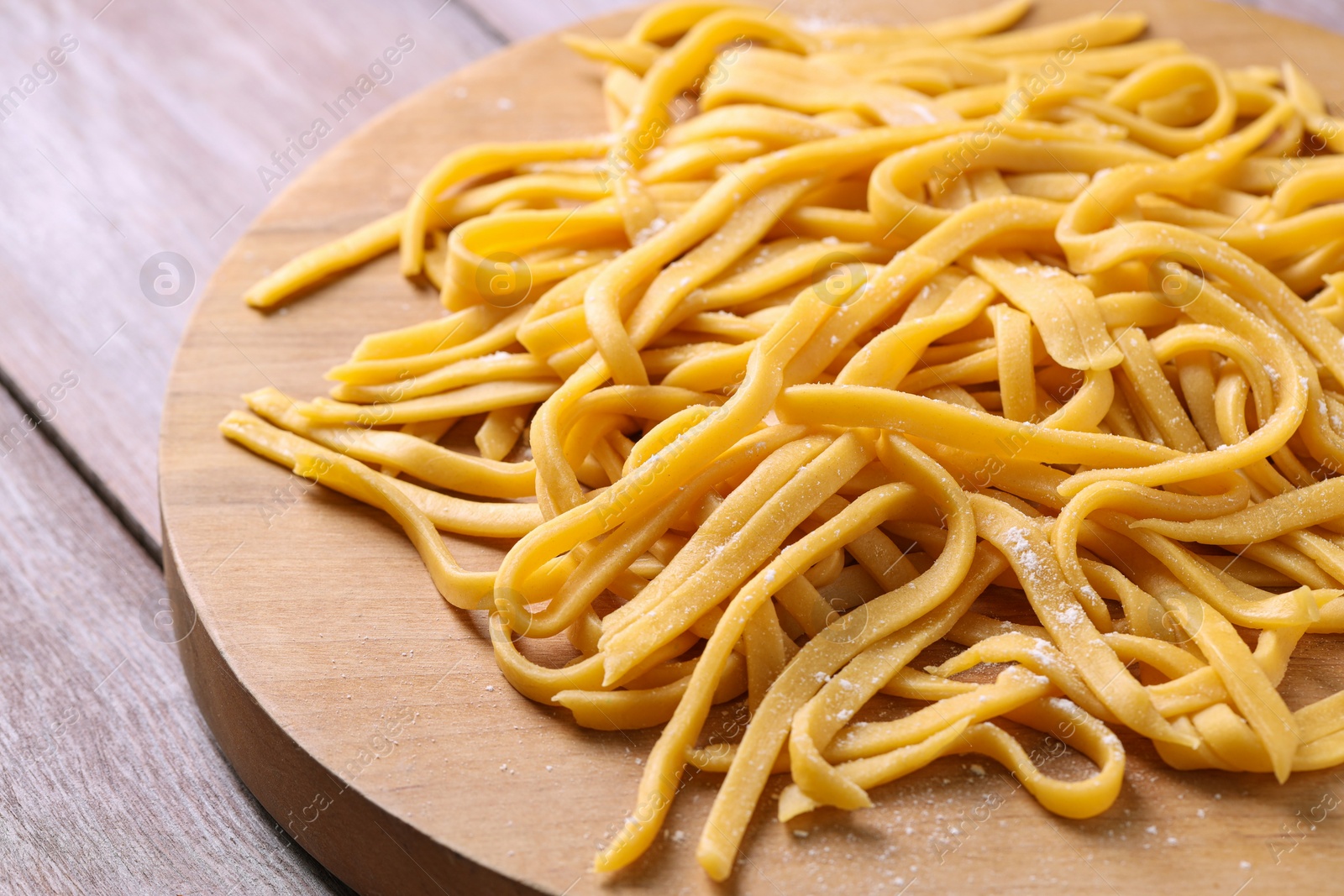 Photo of Board with homemade pasta on wooden table, closeup