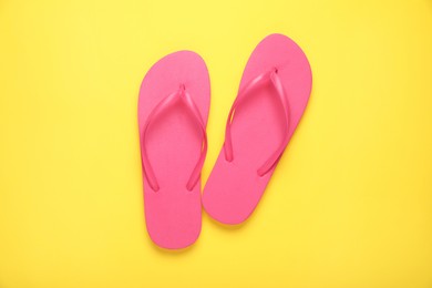 Photo of Stylish pink flip flops on yellow background, top view