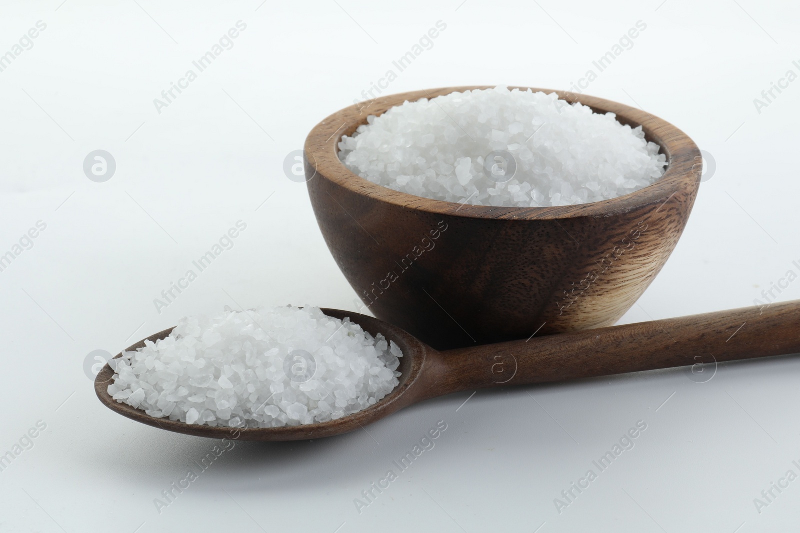 Photo of Natural salt in wooden bowl and spoon isolated on white