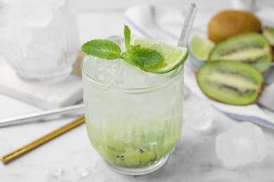 Photo of Glass of refreshing drink with kiwi, lime and mint on white table, closeup