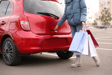 Photo of Woman with shopping bags near her car outdoors, closeup