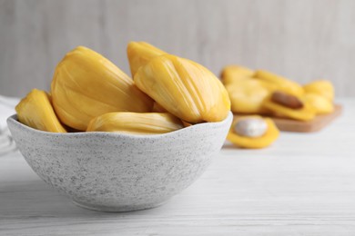 Photo of Delicious exotic jackfruit bulbs on white wooden table