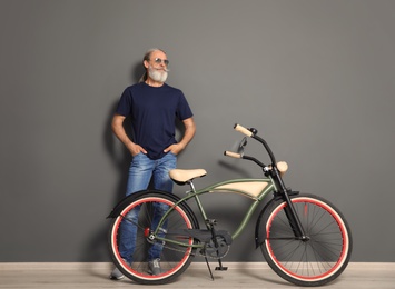 Portrait of handsome mature man with bicycle near color wall
