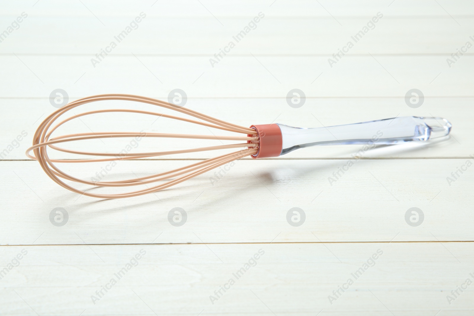 Photo of One whisk on white wooden table, closeup