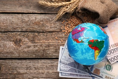 Globe, ears of wheat and banknotes on wooden table, flat lay with space for text. Import and export concept