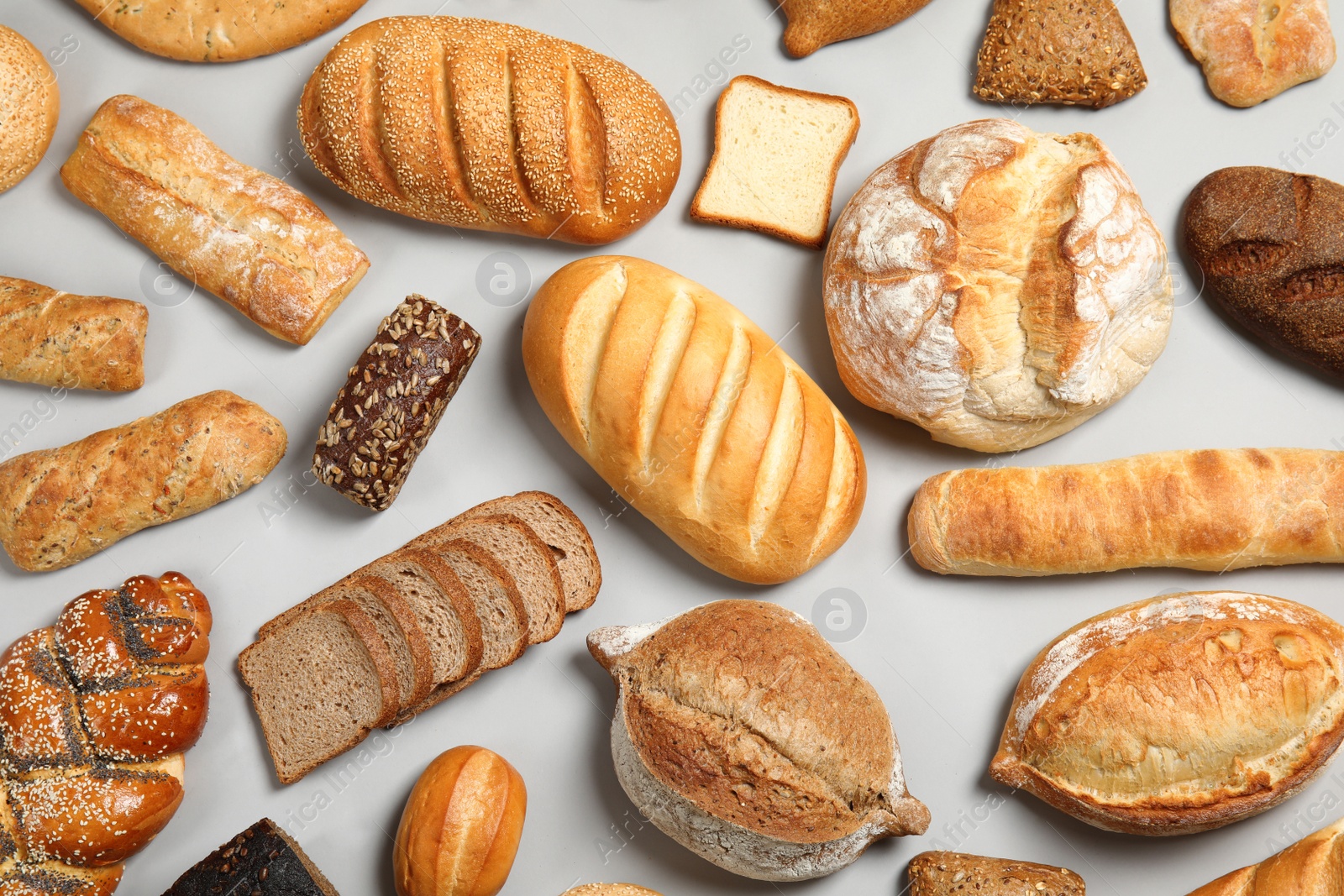 Photo of Different kinds of fresh bread on light background, flat lay