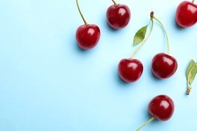 Photo of Delicious cherries on blue background, flat lay. Space for text