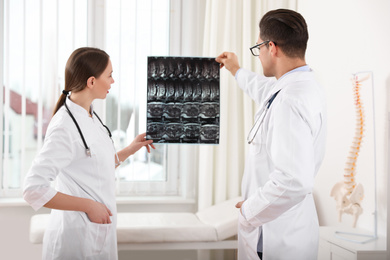 Orthopedists examining X-ray picture near window in office