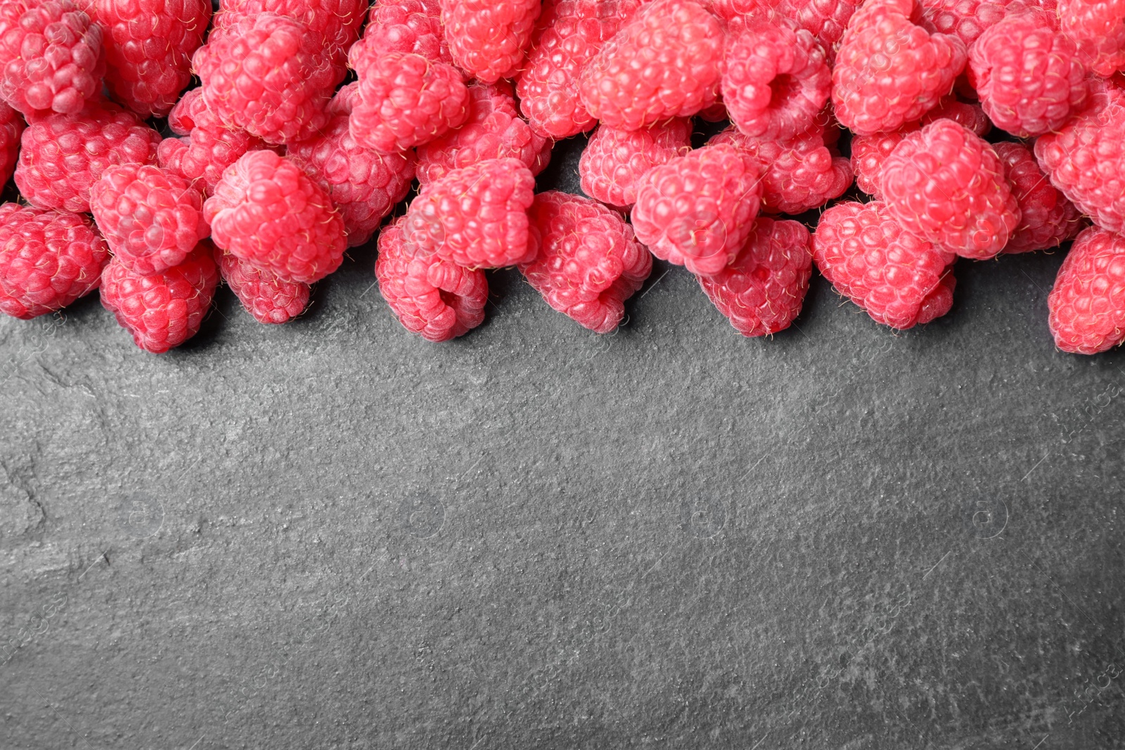 Photo of Delicious fresh ripe raspberries on black table, top view. Space for text