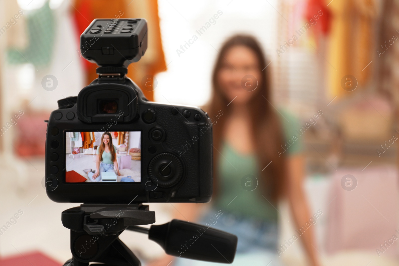 Photo of Fashion blogger recording new video in room, focus on camera