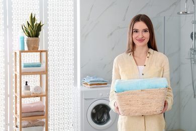 Photo of Happy woman with laundry basket in bathroom