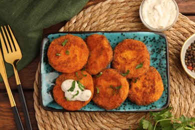 Tasty vegan cutlets served with sauce on wooden table, flat lay