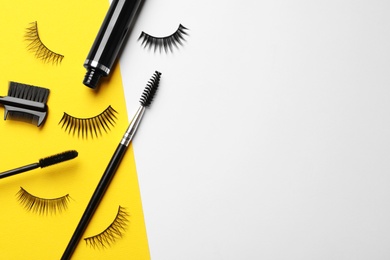 Photo of False eyelashes, mascara and brushes on color background, flat lay. Space for text