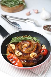 Photo of Delicious homemade sausage with garlic, tomato, rosemary and chili in frying pan on table, closeup